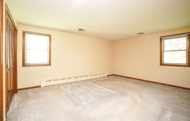 empty room with light colored carpet, visible vents, and baseboard heating