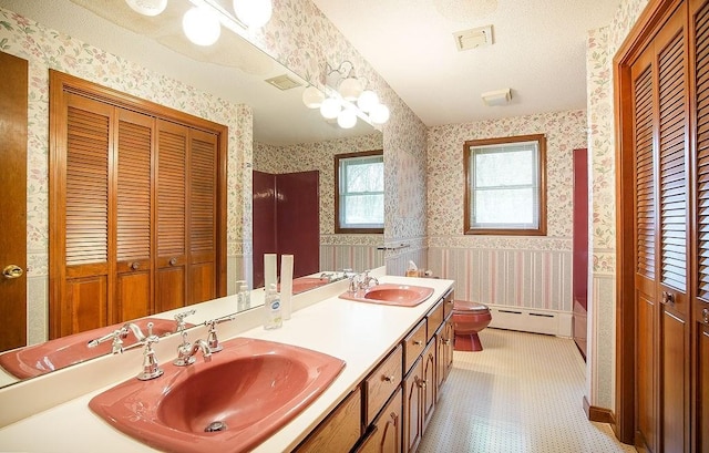 bathroom featuring a sink, a baseboard radiator, a closet, and wallpapered walls