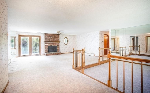 carpeted living room featuring a brick fireplace, wallpapered walls, and ceiling fan