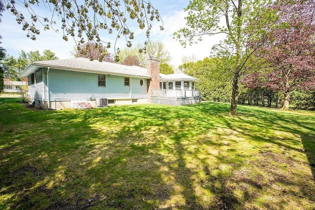 rear view of house featuring a lawn, a wooden deck, central AC, and a chimney