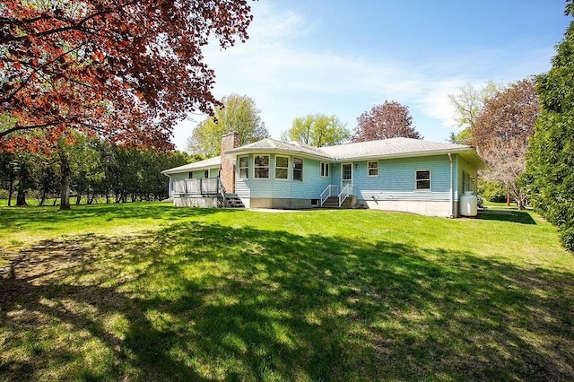 rear view of property featuring a yard and a chimney
