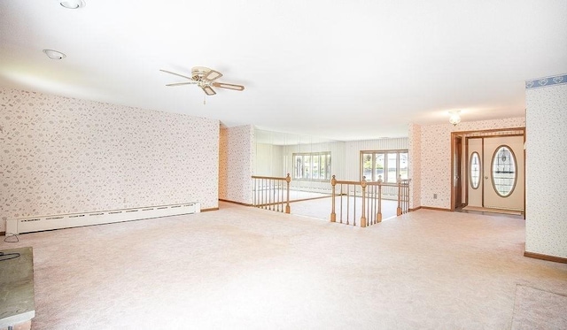 unfurnished living room featuring a ceiling fan, baseboard heating, baseboards, carpet flooring, and wallpapered walls