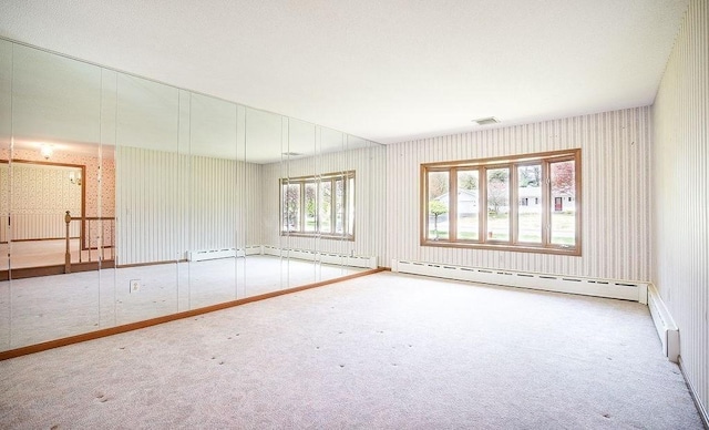 carpeted spare room featuring a baseboard radiator, a baseboard heating unit, wallpapered walls, and visible vents