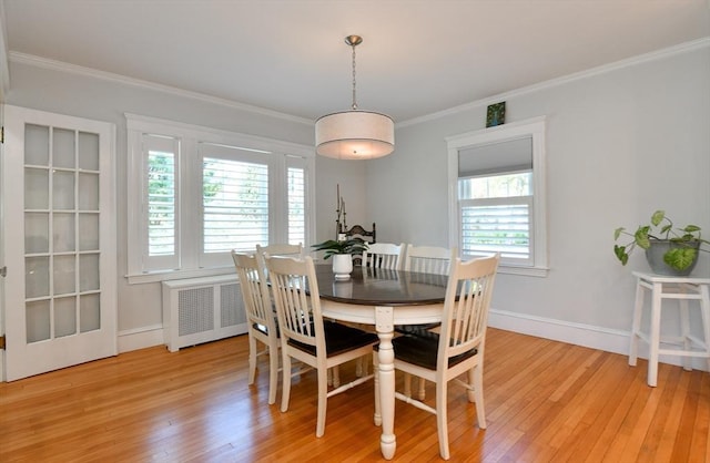 dining space featuring ornamental molding, baseboards, light wood-type flooring, and radiator heating unit