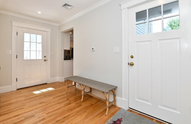 foyer featuring a healthy amount of sunlight, crown molding, light wood-type flooring, and visible vents