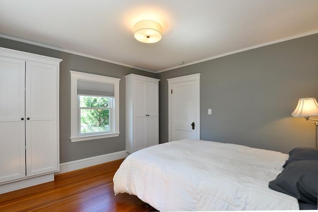 bedroom featuring baseboards, ornamental molding, and dark wood-type flooring