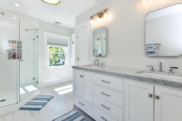 full bathroom with a shower stall, visible vents, a sink, and double vanity