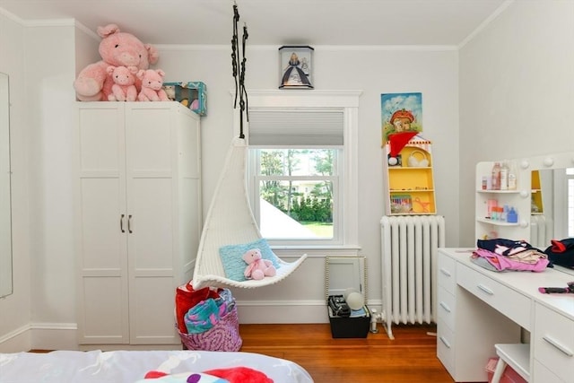 bedroom featuring ornamental molding, wood finished floors, baseboards, and radiator heating unit