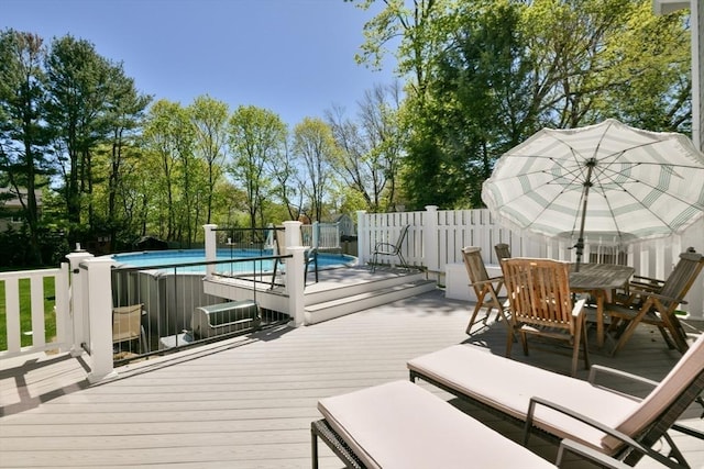 wooden deck featuring outdoor dining area, fence, and a fenced in pool