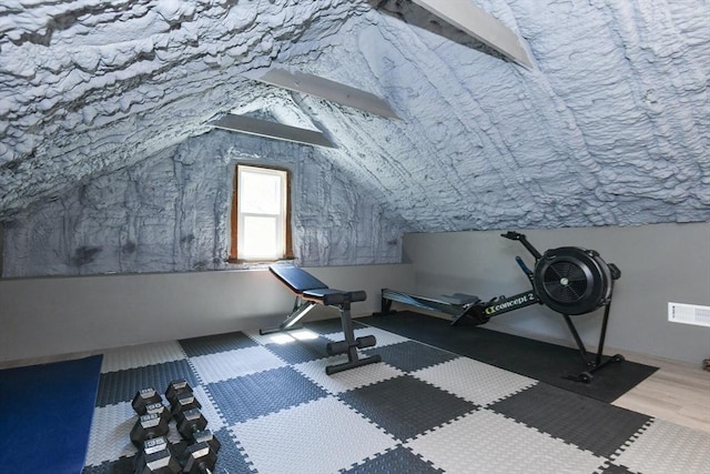 exercise area with vaulted ceiling and wood finished floors
