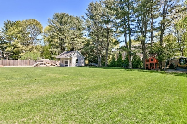 view of yard featuring a playground, an outbuilding, and fence