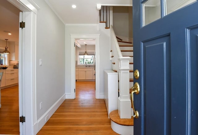 corridor featuring a sink, light wood-type flooring, recessed lighting, stairway, and crown molding