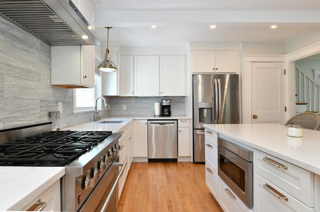 kitchen with under cabinet range hood, white cabinetry, stainless steel appliances, and a sink