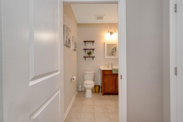 half bathroom with toilet, vanity, baseboards, visible vents, and tile patterned floors