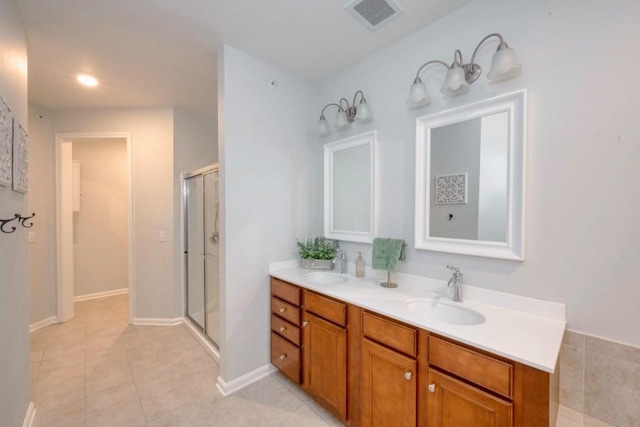 bathroom with double vanity, visible vents, tile patterned floors, a shower stall, and a sink