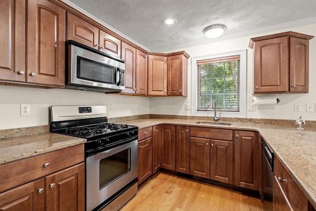 41 Winter Ln Unit 41, Tewksbury, MA 01876 - kitchen featuring stainless steel appliances, a sink, light wood-style floors, light stone counters, and crown molding