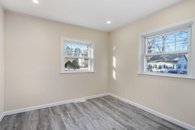 unfurnished room featuring a wealth of natural light, ornamental molding, and hardwood / wood-style floors