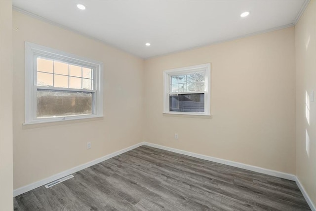 spare room featuring crown molding, a healthy amount of sunlight, and dark hardwood / wood-style flooring