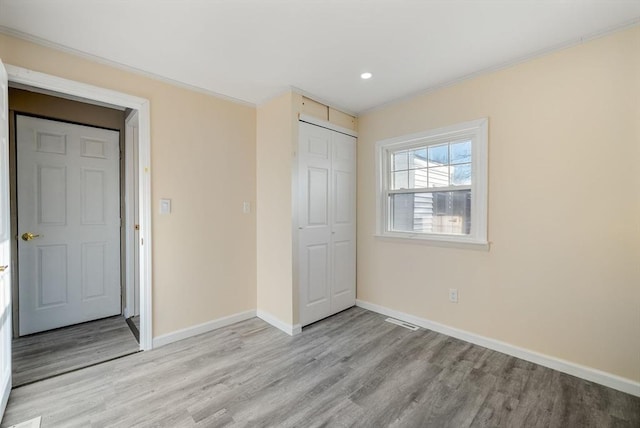 unfurnished bedroom with a closet, crown molding, and light wood-type flooring