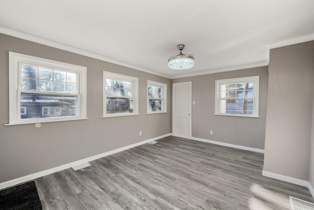 spare room featuring plenty of natural light, light hardwood / wood-style flooring, and ornamental molding