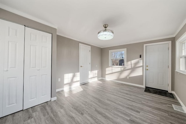 foyer entrance with light hardwood / wood-style floors and ornamental molding