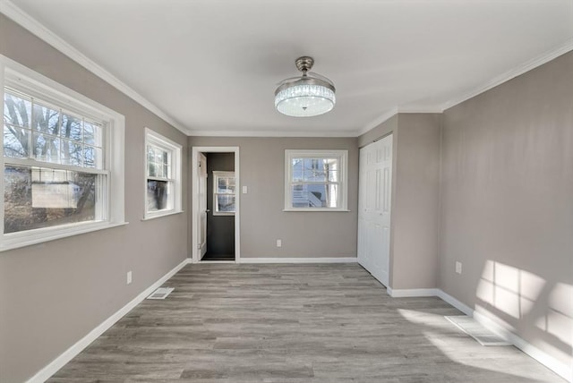 unfurnished room with ornamental molding and light wood-type flooring