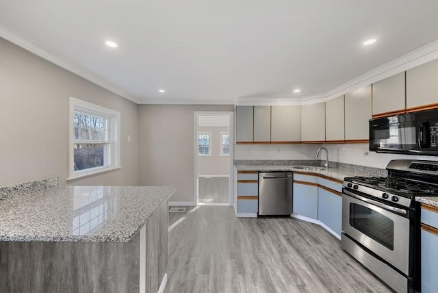 kitchen featuring light stone countertops, sink, ornamental molding, kitchen peninsula, and stainless steel appliances