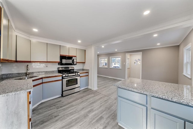 kitchen featuring light stone countertops, sink, ornamental molding, and stainless steel gas range oven