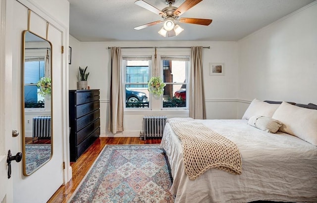 bedroom with crown molding, baseboards, wood finished floors, and radiator