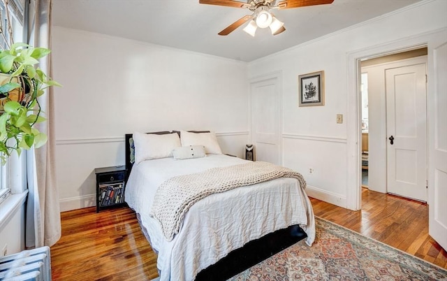 bedroom featuring ceiling fan, baseboards, ornamental molding, and wood finished floors