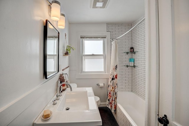 bathroom with visible vents, shower / bath combination with curtain, toilet, baseboards, and a sink