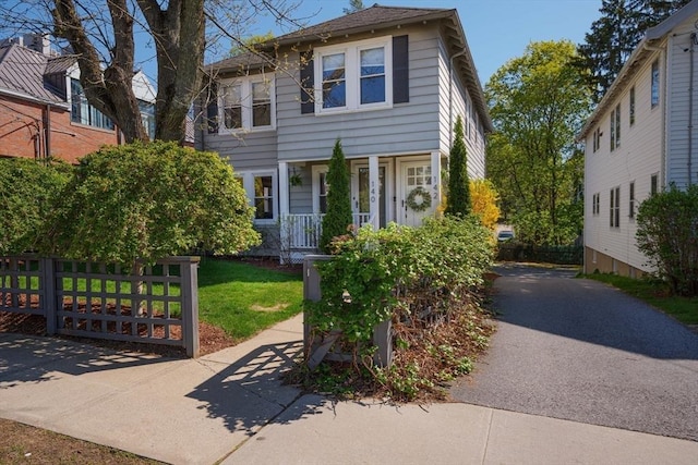 traditional style home featuring fence, a porch, and aphalt driveway