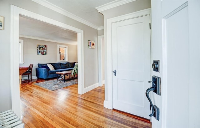 entrance foyer featuring baseboards, ornamental molding, and light wood-style flooring