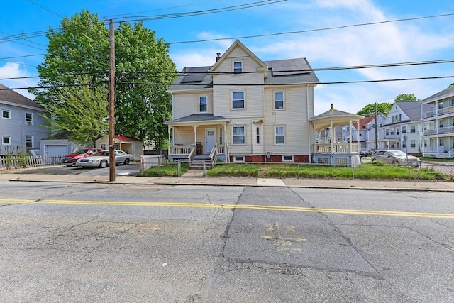 view of front of property with covered porch and solar panels