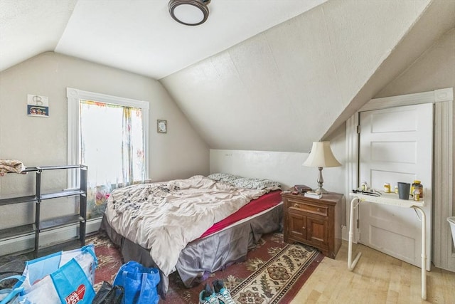 bedroom with vaulted ceiling and wood finished floors