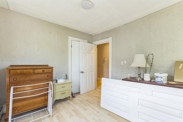 bedroom with wood finished floors and a textured wall