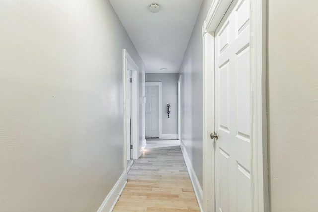 hallway with light wood-type flooring and baseboards