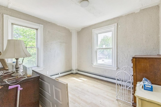 office area featuring wood finished floors, a baseboard heating unit, and a textured wall