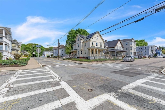 view of asphalt street featuring a residential view, sidewalks, traffic signs, and curbs