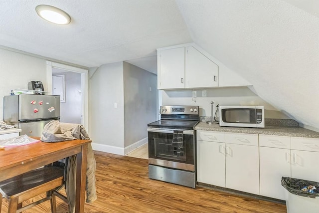 kitchen featuring appliances with stainless steel finishes, light wood-style floors, a textured ceiling, baseboards, and white cabinetry