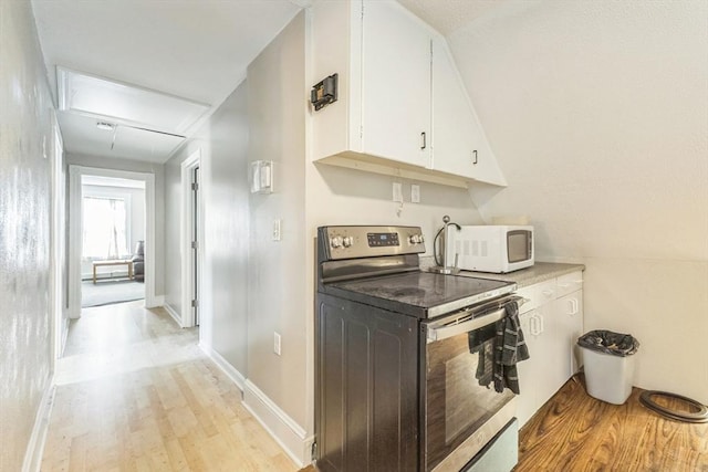 kitchen featuring stainless steel range with electric cooktop, white microwave, light wood-style floors, white cabinetry, and light countertops