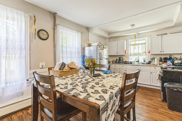 dining room with plenty of natural light, wood finished floors, and a baseboard heating unit
