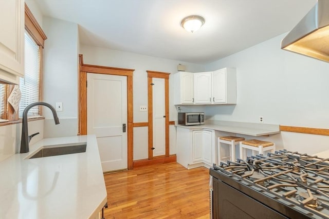 kitchen with white cabinetry, gas stove, light hardwood / wood-style flooring, and sink