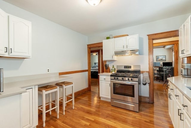 kitchen with gas range, white cabinetry, and light hardwood / wood-style flooring