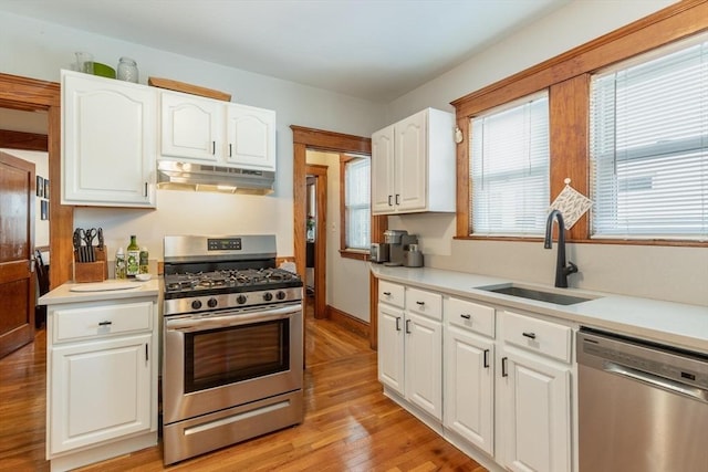 kitchen with white cabinets, sink, stainless steel appliances, and light hardwood / wood-style flooring