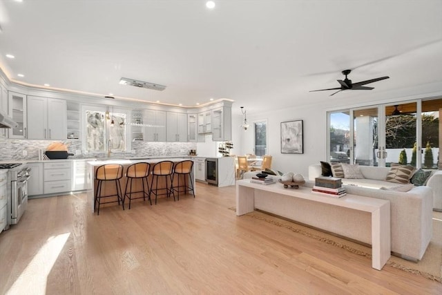 living room featuring wine cooler, ceiling fan, sink, and light hardwood / wood-style flooring