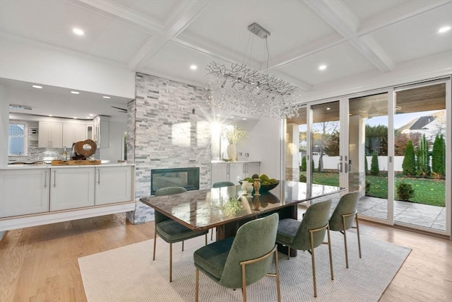 dining room with beamed ceiling, coffered ceiling, a large fireplace, and light hardwood / wood-style flooring