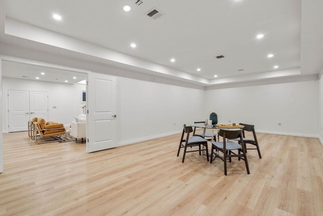 dining space featuring a tray ceiling and light hardwood / wood-style floors