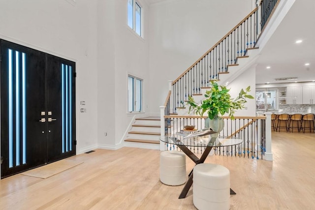 foyer entrance with a towering ceiling and light hardwood / wood-style flooring