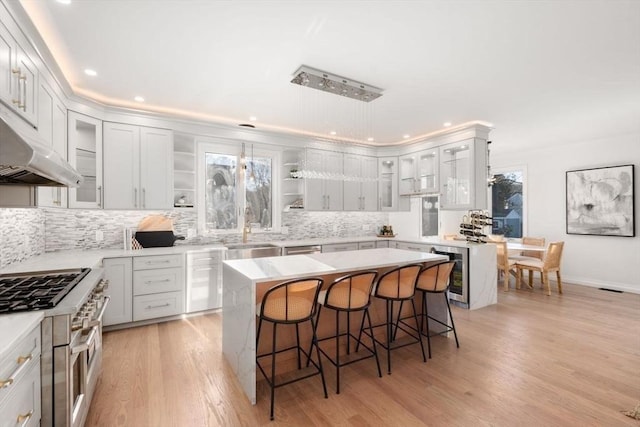 kitchen with white cabinets, a kitchen island, a breakfast bar, and beverage cooler